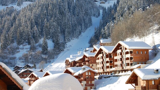 A snow-covered mountain lodge with multiple wooden buildings, a ski slope in the background, and dense evergreen trees. - Magnificent chalet with balcony (Champagny en Vanoise)