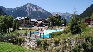 A resort with a swimming pool, surrounded by mountains and greenery. - Magnificent chalet with balcony (Champagny en Vanoise)