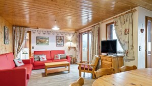 A cozy room with a red sofa, wooden coffee table, and a TV on a wooden cabinet. - Magnificent chalet with balcony (Champagny en Vanoise)