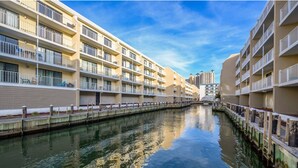 A canal flanked by multi-story buildings with balconies, reflecting the sky and buildings.