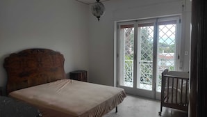 A bedroom with a bed, a wooden headboard, a small table, and a balcony with a view. - Apartment between Herculaneum and Pompeii at fields of Vesuvius (Torre del Greco)