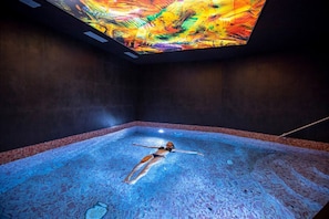 A person floating in a large indoor pool with a colorful ceiling. - Cozy Suite on the Slopes (Bourg-Saint-Maurice)