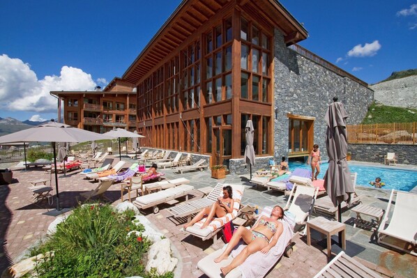 A resort with a pool area, lounge chairs, and a building with large windows.
