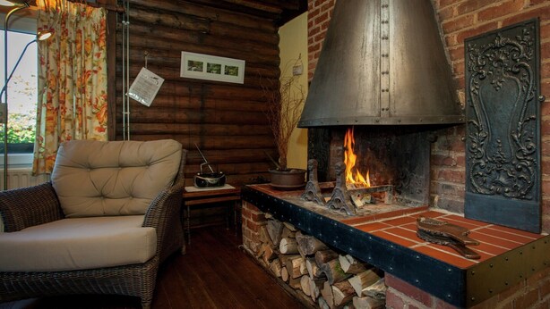 A cozy room with a fireplace, a wicker chair, and a rustic brick wall. - Cozy Chalet in Francorchamps (Stavelot-Neuville)