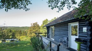 A log cabin with a porch, outdoor seating, and a view of the surrounding landscape. - Cozy Chalet in Francorchamps (Stavelot-Neuville)