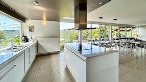 A modern kitchen with a central island, large windows, and a dining area with outdoor seating. - Villa in Coo with Pool & Panoramic Views (Coo - Stavelot)