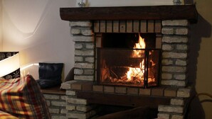 A fireplace with a stone surround, a sofa with striped cushions, and a lamp on a side table.