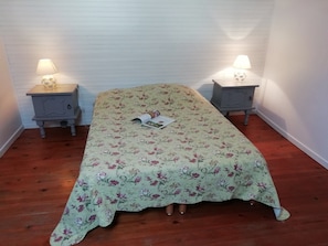 A single bed with a floral bedspread, two bedside tables with lamps, and a white wall. - Holiday Home in Quend near Forest and Sea (Quend-Plage)