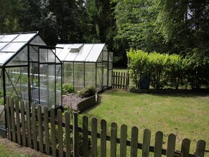 A greenhouse with a wooden fence and a garden area. - Holiday Home in Quend near Forest and Sea (Quend-Plage)