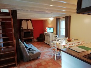 Ein gemütliches Wohnzimmer mit Kamin, einer Essecke mit Tisch und Stühlen sowie einem Fernseher auf einem Schrank.