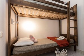 A bunk bed with a ladder, a pillow, a stuffed toy, a blanket, and a book.
