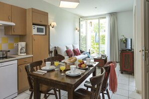 A dining area with a table set for breakfast, a microwave, and a coffee maker in the kitchen. - Apartment in Bergheim near Alsace Vineyards (Bergheim)
