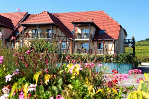Un hotel de varios pisos con balcones, una piscina y cielo despejado.
