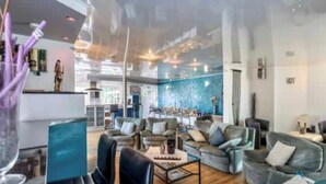 A spacious hotel lobby with multiple seating areas, a bar, and a large window with a view. - House in Moulin du Ruy with Forest Views (Stoumont-Moulin du ruy)