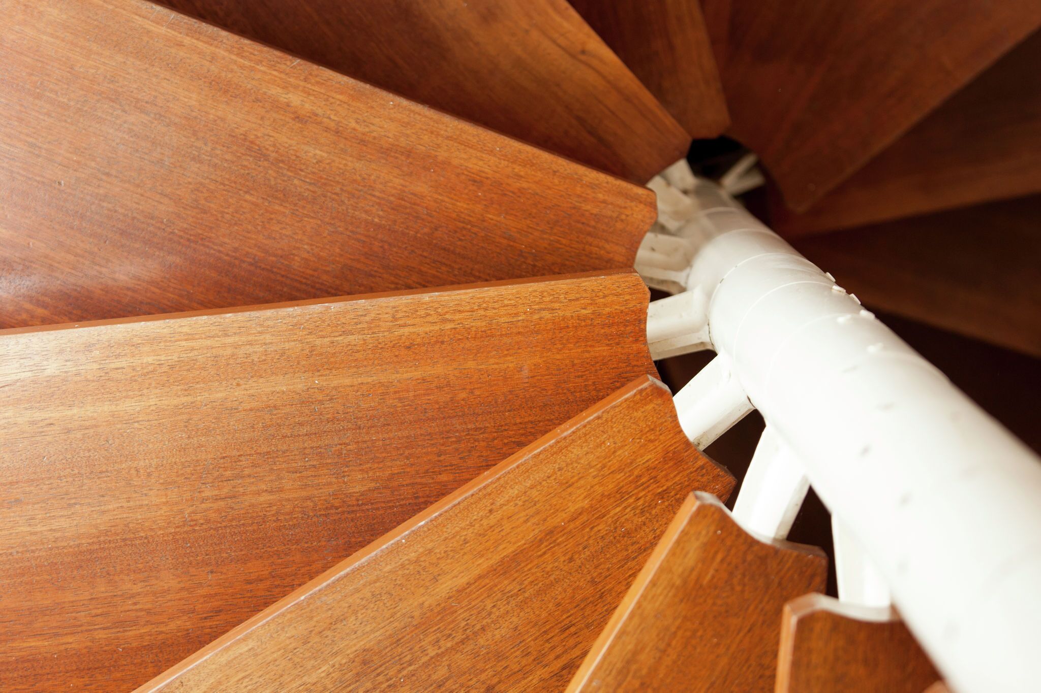 A spiral staircase with wooden steps and white handrails.