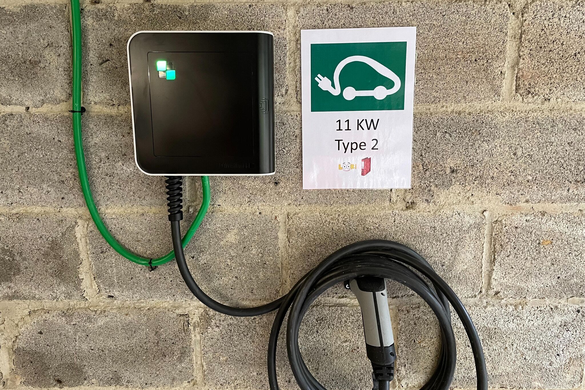 An electric vehicle charging station with a sign indicating it is a Type 2 charger with a 11 kW capacity.