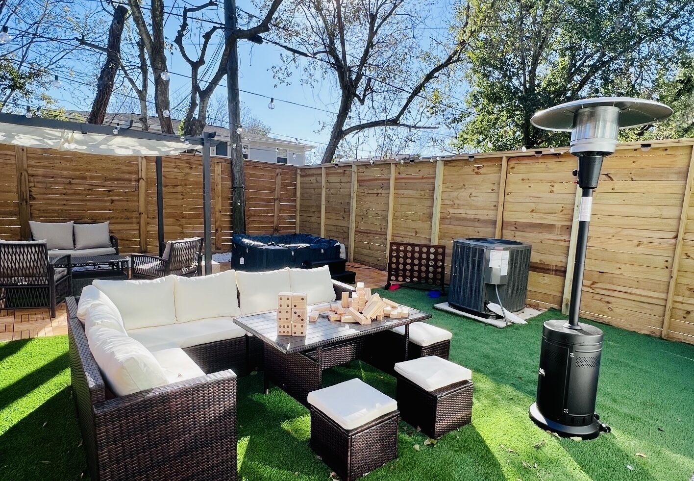 A backyard with a patio area, outdoor furniture, a fire pit, and a heater.