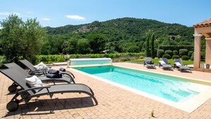 A pool area with lounge chairs, a pergola, and a view of a vineyard and hills. - Holiday Home in Le Plan-de-la-Tour with Pool (Le Plan-De-La-Tour)