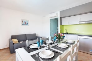 Una cocina moderna con comedor, un sofá gris y un cuadro en la pared.