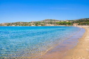 A beach with clear blue water and a sandy shore.