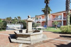 Ein Innenhof mit einem Steinfbrunnen, Palmen und einem Gebäude mit Balkonen.