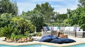 Ein Poolbereich mit Holzterrasse, einer Couch mit Kissen und einem kleinen Tisch.
