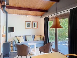 A modern living room with a sofa, two chairs, a table, a large window, and a ceiling vent.