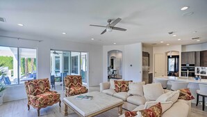 A spacious living room with a large sofa, armchairs, and a coffee table. There is a ceiling fan, a kitchen area with modern appliances, and large windows offering a view of the outdoors. - Private Pool & Spa: Spacious Home in Bermuda Dunes (Bermuda Dunes)