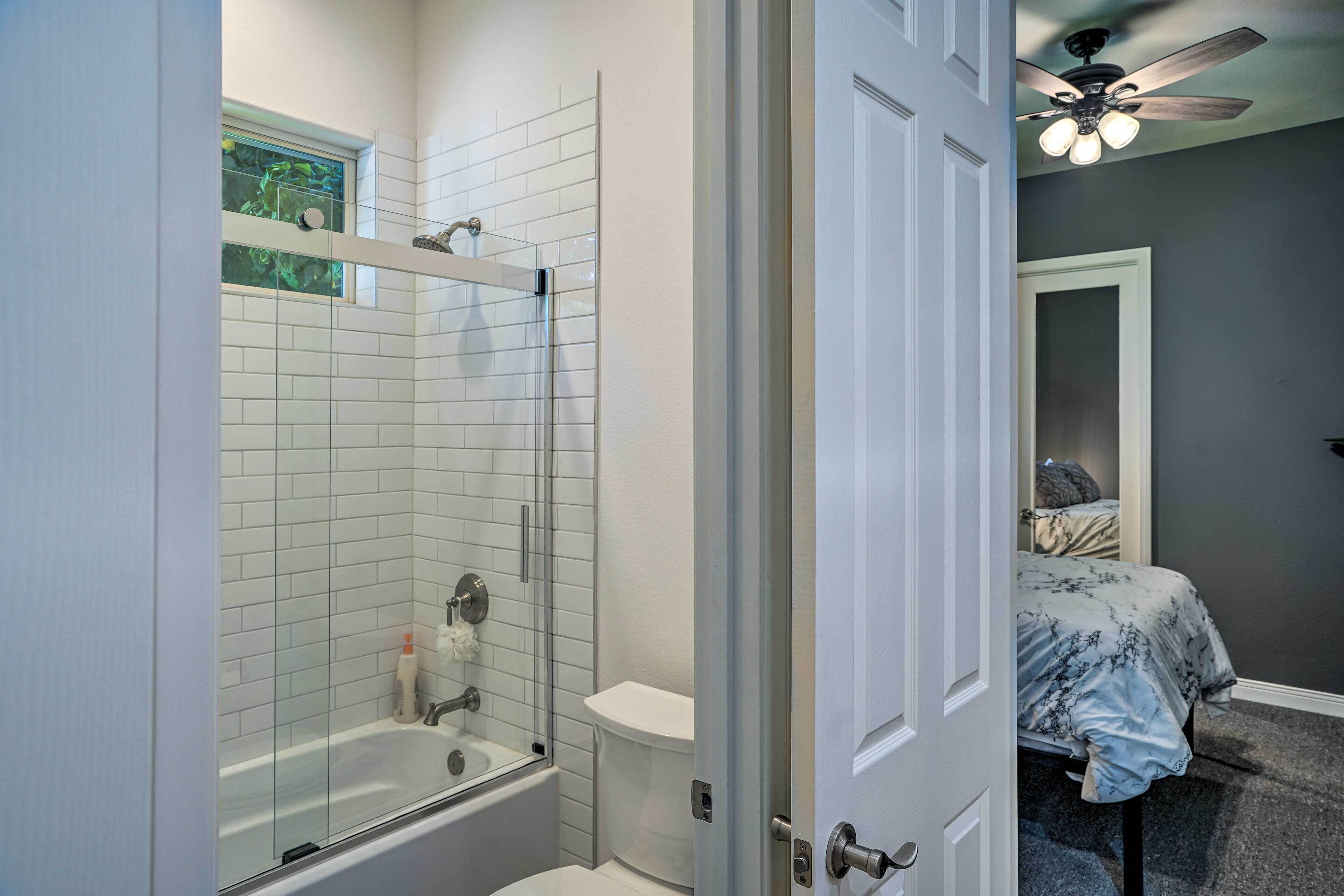 A bathroom with a glass-enclosed shower, a white bathtub, and a toilet.