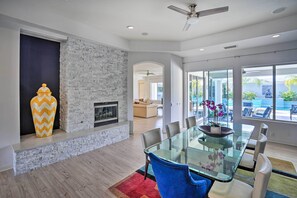 A modern dining area with a glass table, blue chairs, and a fireplace. - Private Pool & Spa: Spacious Home in Bermuda Dunes (Bermuda Dunes)