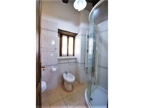 Une salle de bain comprenant des toilettes, un bidet et une douche séparée par une paroi en verre.