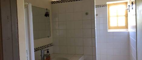 Un baño con lavamanos, espejo y una ventana pequeña.