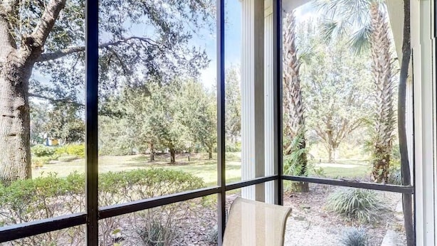 Una habitación con un amplio ventanal que ofrece vistas a un jardín ajardinado con diversas especies de árboles y arbustos.