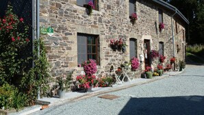 Un bâtiment en pierre doté de nombreuses fenêtres, dont certaines sont ornées de jardinières. Une enseigne indique qu’il s’agit d’un restaurant ou d’un café.