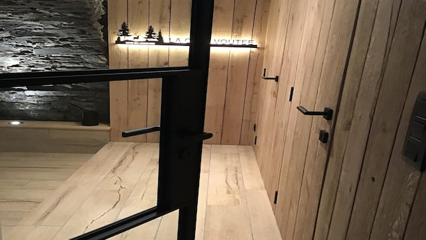 Un intérieur moderne avec des murs recouverts de panneaux en bois, un mur en pierre servant d’élément décoratif, et un plancher en bois.