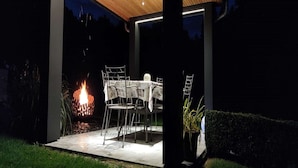 Une terrasse extérieure avec une table et des chaises, un foyer et un plafond en bois.