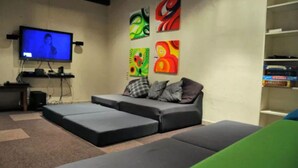 Una sala de estar con un sofá modular, un televisor de pantalla plana y arte abstracto de colores en las paredes.