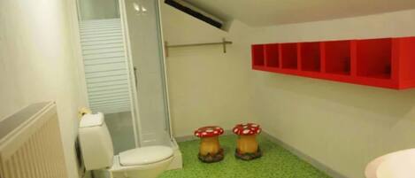 A bathroom with a toilet, shower, and a red shelf unit.