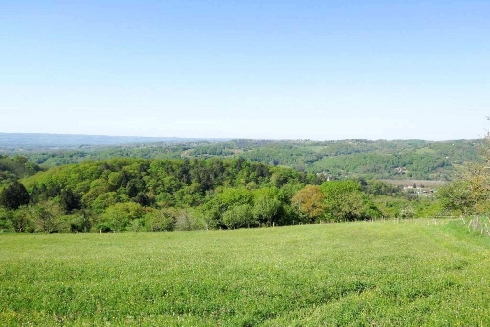 A panoramic view of a green landscape with rolling hills and a clear sky.