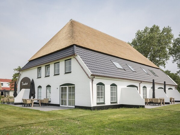 A white building with a sloped roof and multiple windows. - Apartment in De Cocksdorp near Beach (De Cocksdorp Texel)
