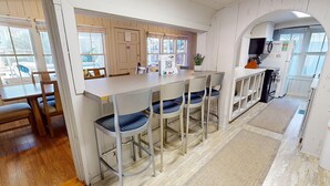 A kitchen with a bar area, wooden flooring, and a view of the outdoors.