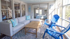 A covered porch with a sofa, chairs, and a table.