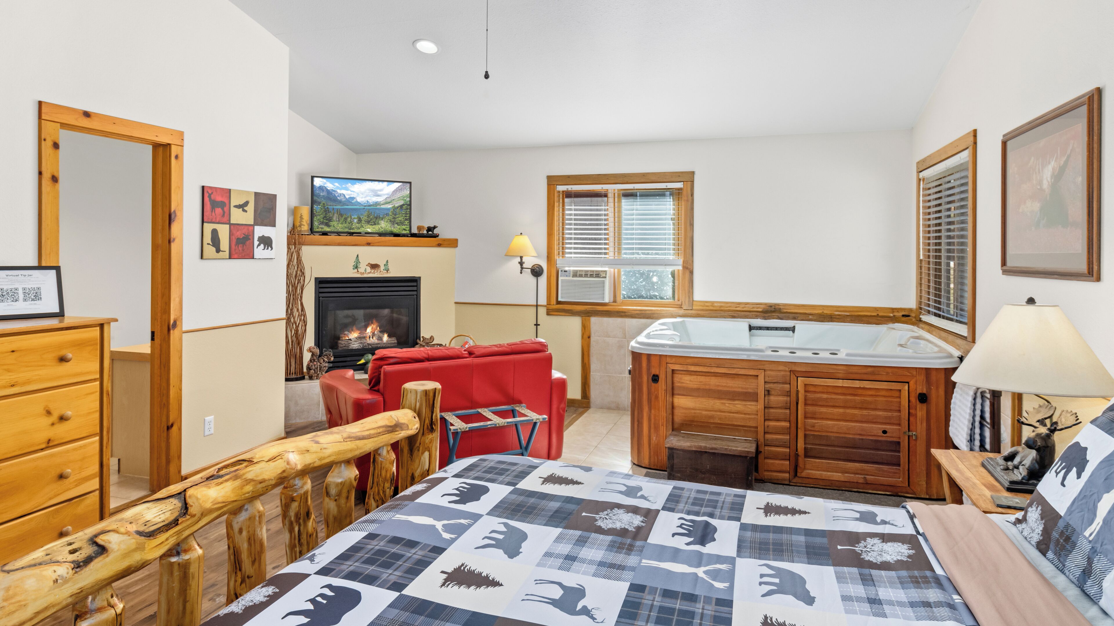 Una habitación acogedora con chimenea, un sofá rojo, una mesa de madera y una cama grande con colcha.