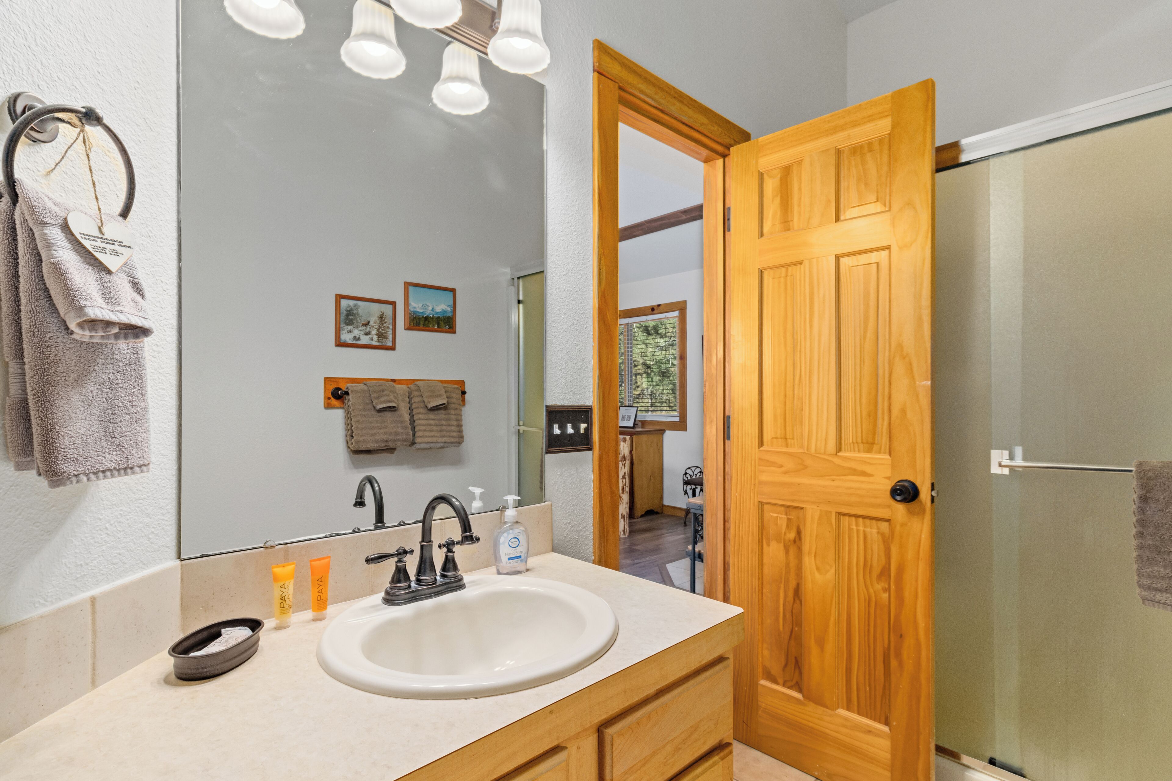 A bathroom with a sink, mirror, towel rack, and wooden door.
