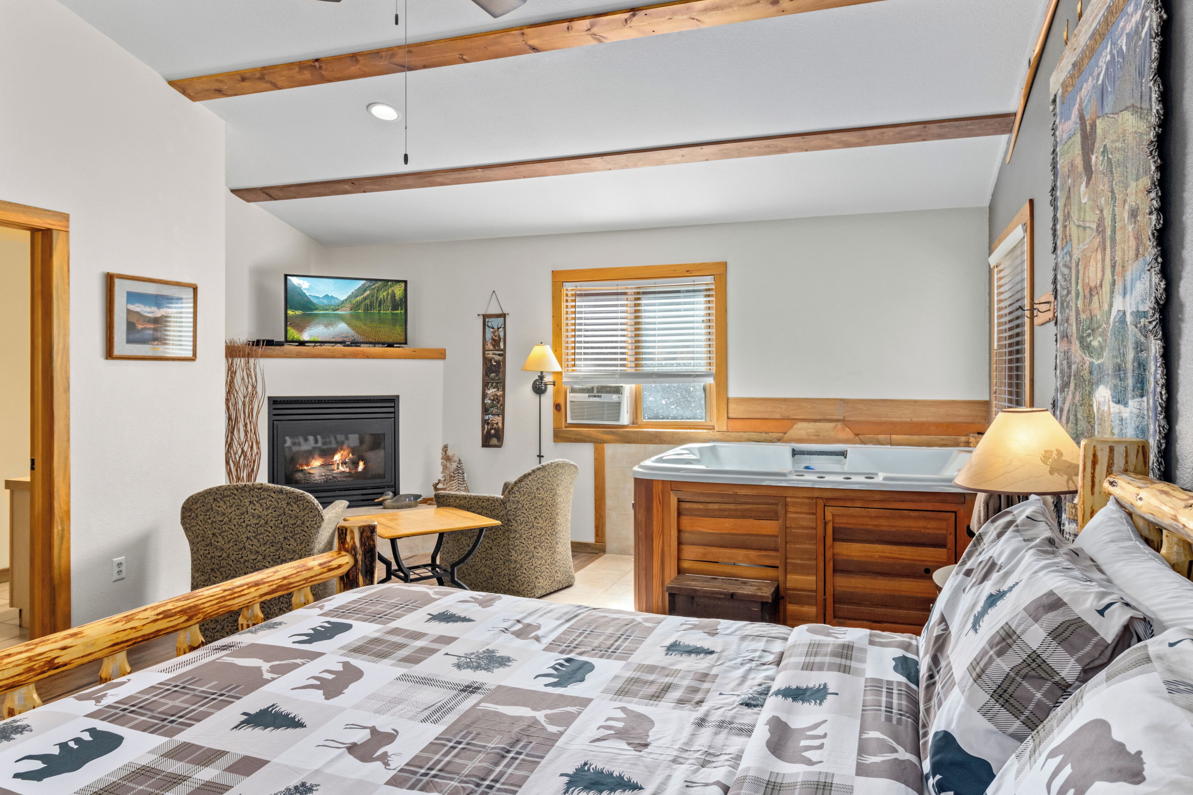 A cozy room with a bed, a fireplace, a TV, a dining area, and a bathroom.