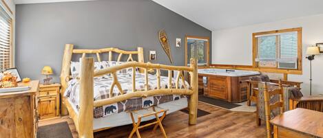 Una habitación rústica de estilo cabaña con una cama de madera, un jacuzzi y un comedor.