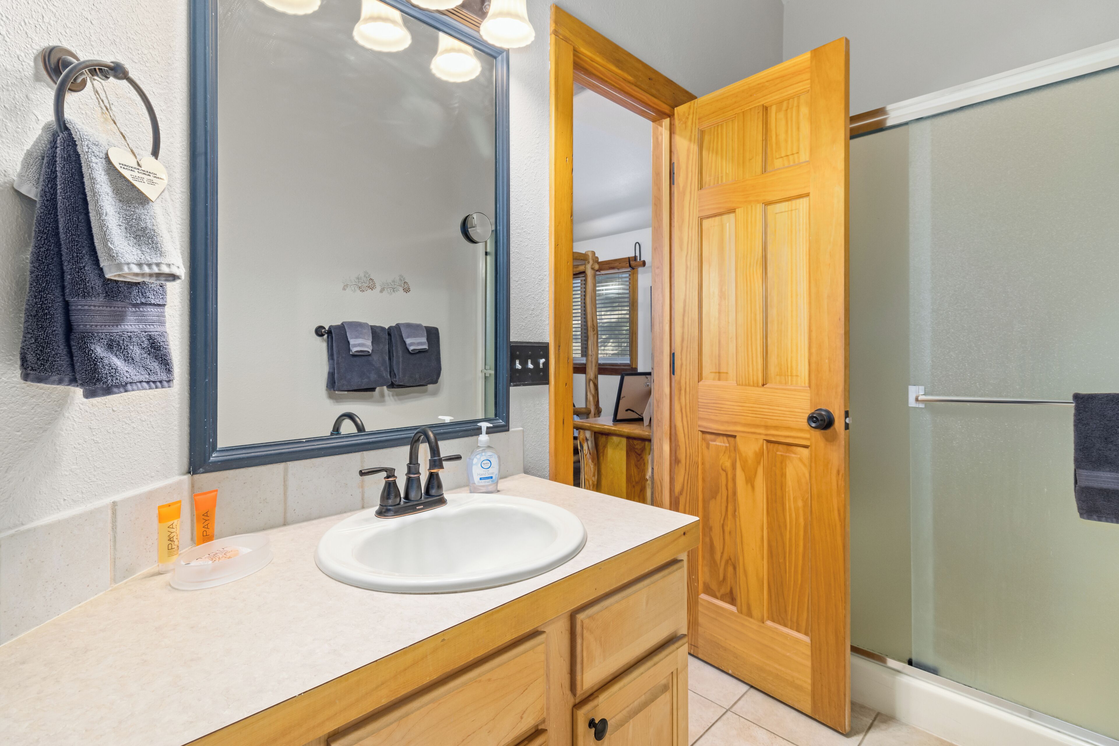 Un baño con lavamanos, espejo y armarios de madera.