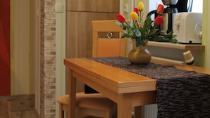 Una mesa de madera con un florero de tulipanes, una cafetera y un tostador sobre una encimera de cocina.