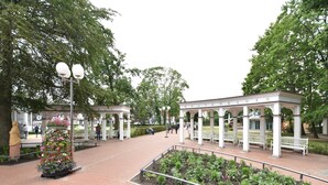 Un parque con un pabellón, bancos y parterres de flores.