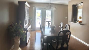 A dining area with a wooden table and chairs, a chandelier, and a potted plant.
